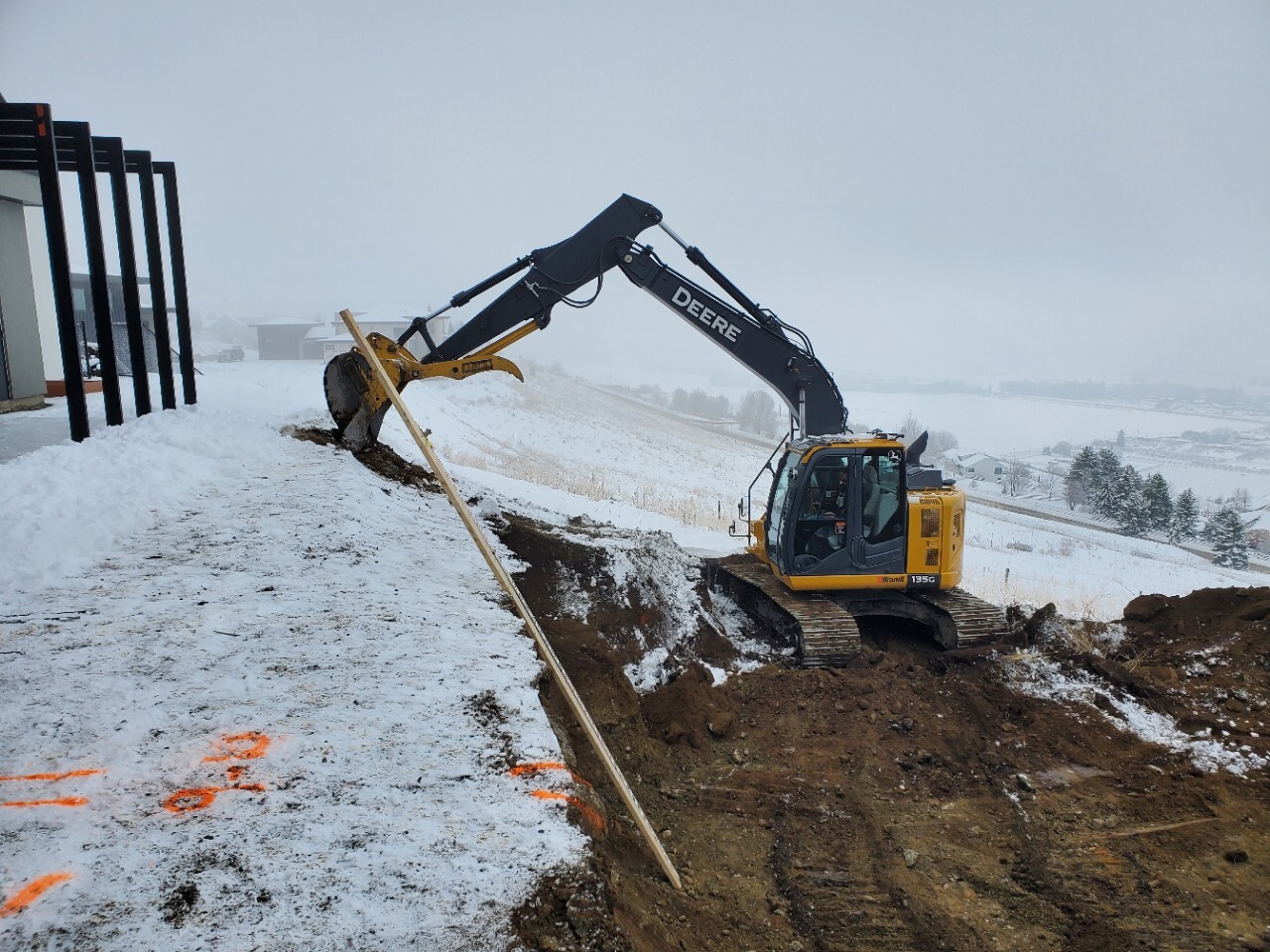 A yellow and black excavator digging in the snow