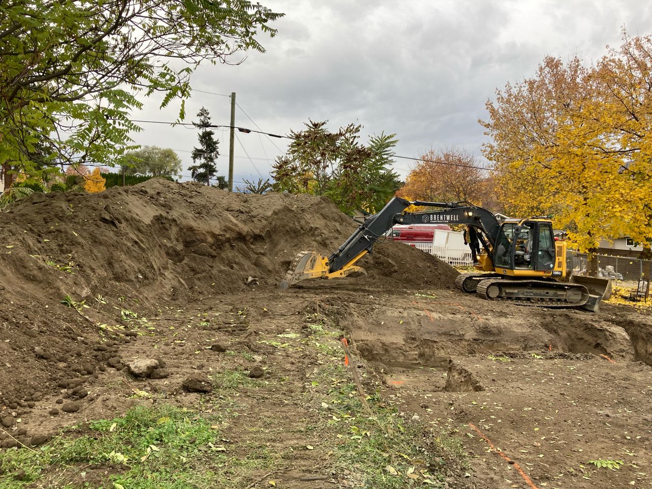 A yellow and black excavator digging in the fall