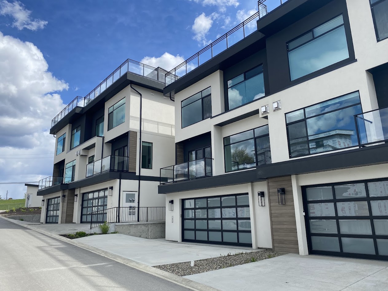 a modern white stucco townhome complex with glass doors